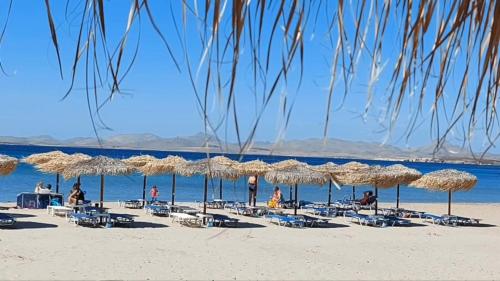 a beach with chairs and umbrellas and people on it at Amari Stone Apartments in Moudhros