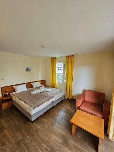 a bedroom with a bed and a red chair at Family Hotel Romantik in Sunny Beach