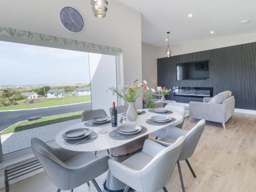 a dining room with a white table and chairs at Number 6 Villa - The View in Doirí Beaga