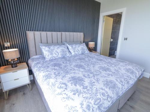 a bedroom with a bed with a blue and white comforter at Number 6 Villa - The View in Doirí Beaga