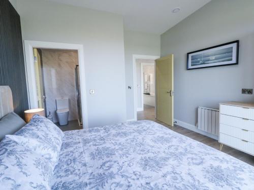 a bedroom with a bed with a blue and white blanket at Number 6 Villa - The View in Doirí Beaga
