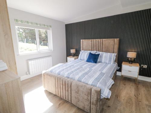 a bedroom with a large bed with blue pillows at Number 6 Villa - The View in Doirí Beaga