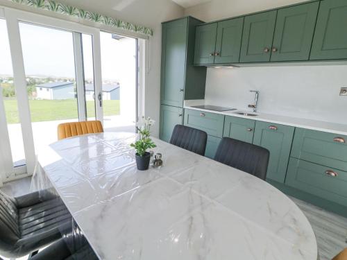 a kitchen with a large marble table and green cabinets at Number 3 Villa - The View in Doirí Beaga