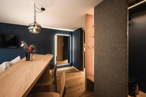 a dining room with a wooden table and blue walls at The Post Mountain Residence in Dobbiaco