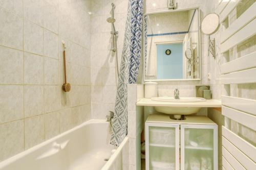 une salle de bain avec un lavabo, une baignoire et un miroir dans l'établissement Appartement Lumiere - 10 min château, à Versailles