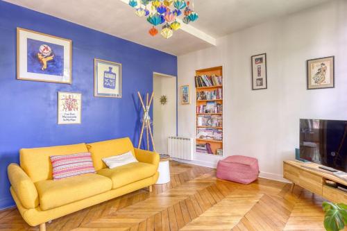 - un salon avec un canapé jaune et une télévision dans l'établissement Appartement Lumiere - 10 min château, à Versailles