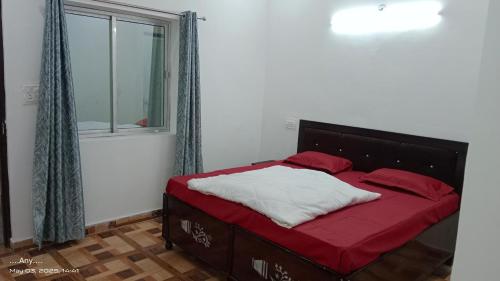 - une chambre avec un lit doté de draps rouges et une fenêtre dans l'établissement Kedar view inn, à Phata