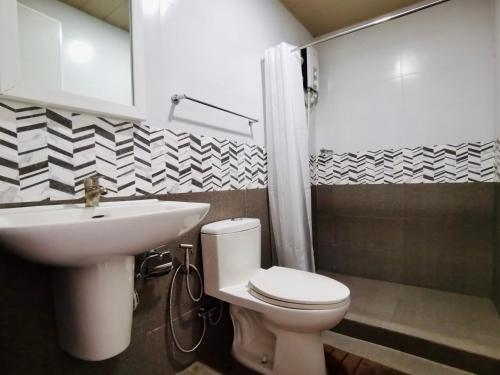 a bathroom with a white toilet and a sink at Den Den Guesthouse in Basco