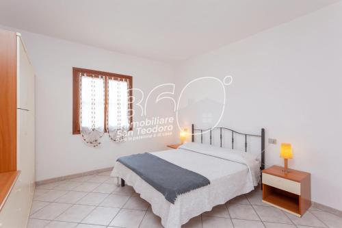 a white bedroom with a bed and a window at Portico 2 in San Teodoro