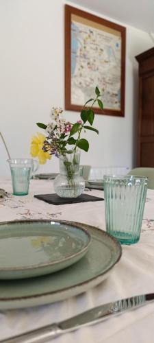 une table avec deux assiettes et un vase de fleurs dans l'établissement Maison Irondas, à Saint-Pierre-dʼAurillac