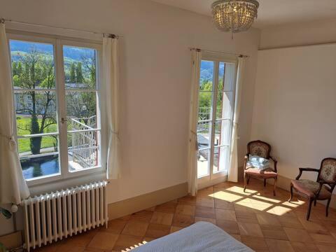 a room with two windows and a bed and a chair at VILLA Turmmattli in Sarnen