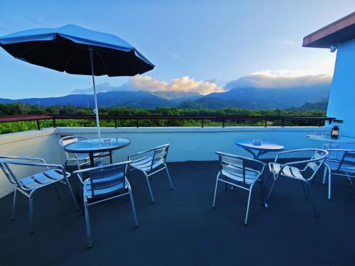 a patio with tables and chairs and an umbrella at Cloud Tree Inn Boutique Guesthouse XiChong DaPeng ShenZhen 深圳大鹏西涌云树里民宿Yun Shu Li in Shenzhen