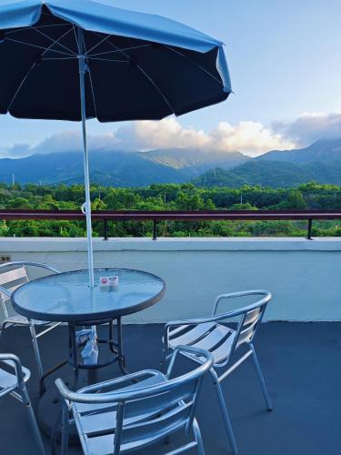 a table and chairs with an umbrella on a balcony at Cloud Tree Inn Boutique Guesthouse XiChong DaPeng ShenZhen 深圳大鹏西涌云树里民宿Yun Shu Li in Shenzhen