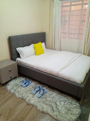a bed with blue slippers on a rug in a bedroom at Gardenview Homes -2 Bedroom Apartment along Nyeri-Nanyuki Road -Kingongo in Nyeri