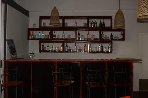 a bar with two chairs and bottles on shelves at Blackstone Sands Resort Bilene in Vila Praia Do Bilene