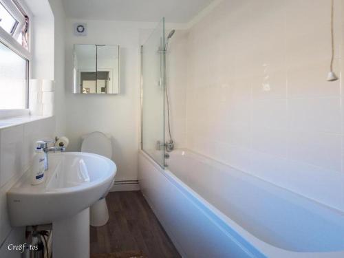 a white bathroom with a sink and a bath tub at 12 Cornwallis Lodge Family Room 1 in Stoke on Trent