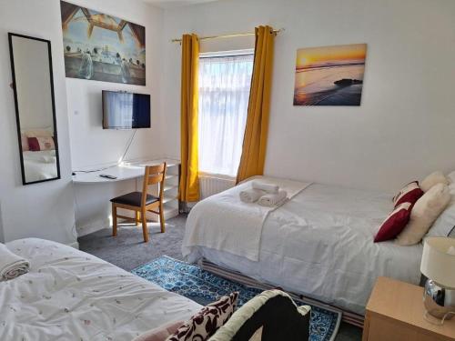 a bedroom with two beds and a desk and a window at 12 Cornwallis Lodge Family Room 1 in Stoke on Trent
