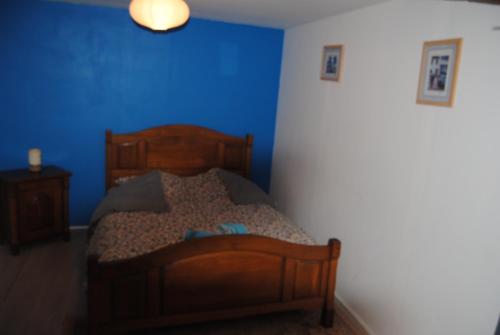 une chambre avec un lit en bois avec un mur bleu dans l'établissement maison de campagne, à La Celle-sous-Gouzon
