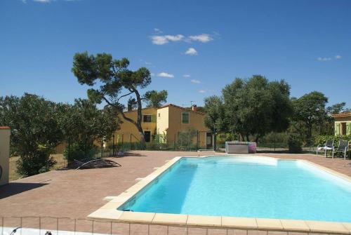 a swimming pool in front of a house with trees at Domaine Saint Antoine in Rieux-Minervois