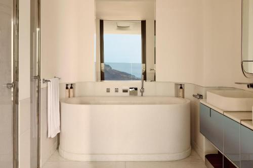 a large white tub in a bathroom with a window at The Maybourne Riviera, Maybourne in Roquebrune-Cap-Martin