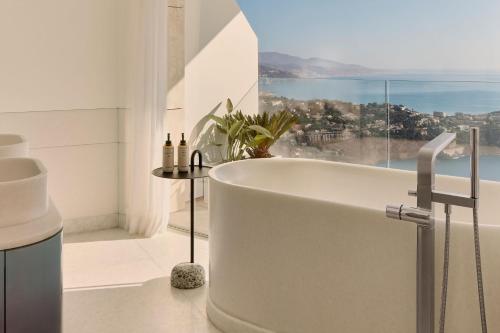 a bathroom with a bath tub in front of a window at The Maybourne Riviera, Maybourne in Roquebrune-Cap-Martin