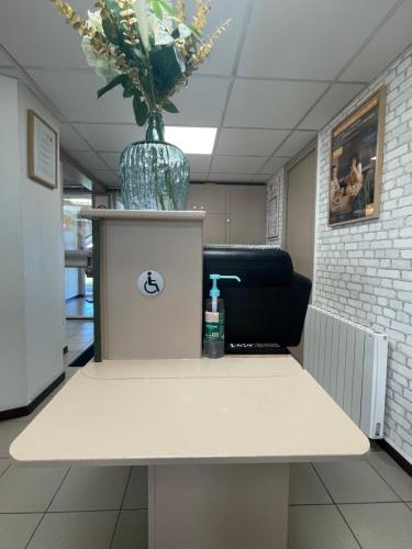 a table with a vase of flowers on top of it at Premiere Classe Amiens Est - Glisy in Glisy