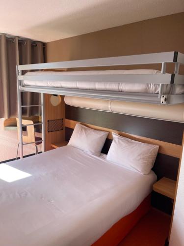 a bedroom with two bunk beds with white sheets at Premiere Classe Amiens Est - Glisy in Glisy