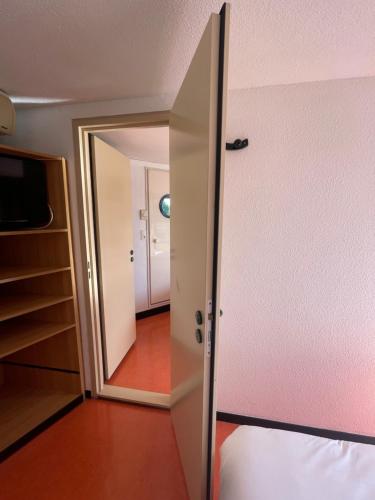 an open door to a bedroom with a mirror at Premiere Classe Amiens Est - Glisy in Glisy