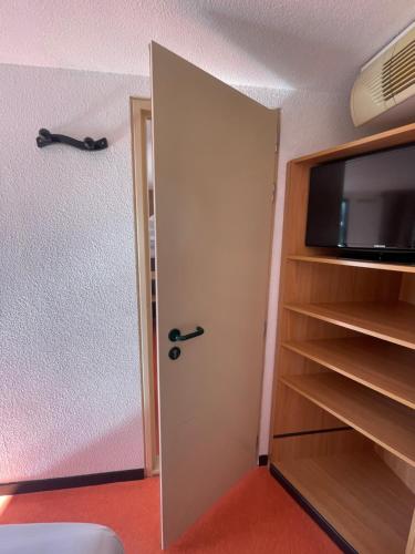 a room with a flat screen tv and a closet at Premiere Classe Amiens Est - Glisy in Glisy