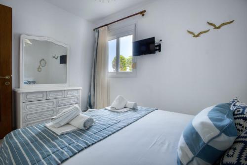 a bedroom with a bed with a dresser and a mirror at Maison Ciel in Agia Paraskevi