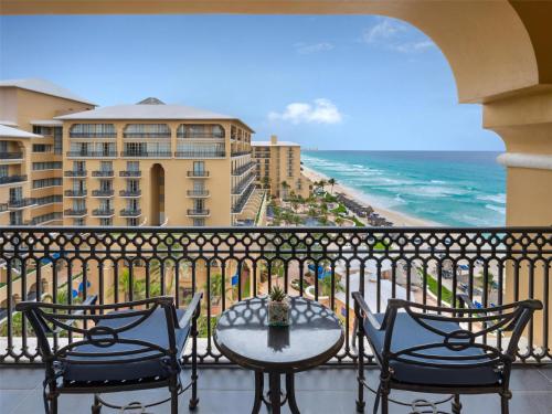 a balcony with a table and chairs and the ocean at Kempinski Hotel Cancun in Cancún