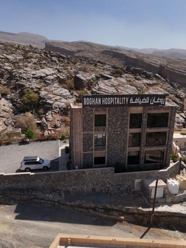 a building with a car parked in a parking lot at Roghan Hospitality Inn in Al Ḩamrāʼ