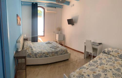 a bedroom with two beds and a desk and a window at BorgoMarino's Room in Cefalù