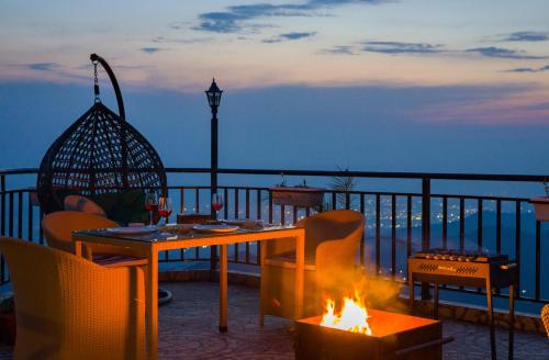 a table and chairs around a fire pit on a balcony at Alaya Stays Archee's 6 BHK Nature Retreat with Game Lounge & Open Dining in Kasauli