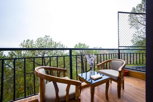 two chairs and a table on a balcony with a view at Alaya Stays Archee's 6 BHK Nature Retreat with Game Lounge & Open Dining in Kasauli