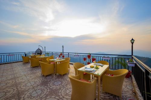 a restaurant with tables and chairs on a balcony at Alaya Stays Archee's 6 BHK Nature Retreat with Game Lounge & Open Dining in Kasauli
