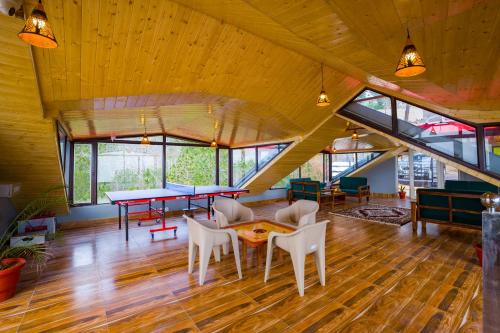 a large room with tables and chairs and windows at Alaya Stays Archee's 6 BHK Nature Retreat with Game Lounge & Open Dining in Kasauli