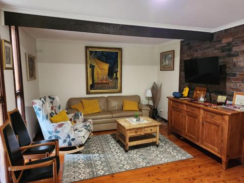 a living room with a couch and a tv at A Holiday Home for Every Season in Bateau Bay