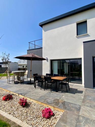 un patio avec tables, chaises et un parasol dans l'établissement villa des rivages, à Cléder