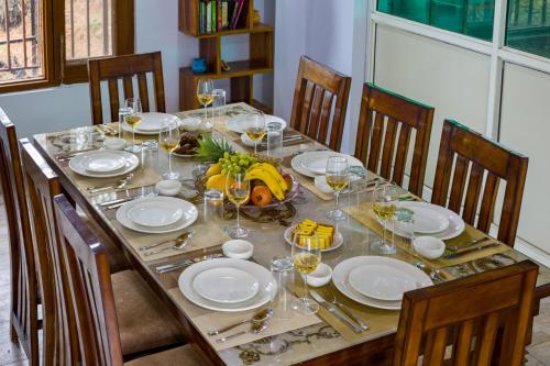 a table with plates of food and glasses of wine at Alaya Stays Archee's 6 BHK Nature Retreat with Game Lounge & Open Dining in Kasauli