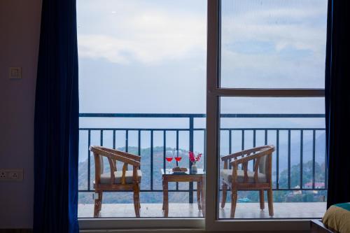 a view of a table and two chairs on a balcony at Alaya Stays Archee's 6 BHK Nature Retreat with Game Lounge & Open Dining in Kasauli