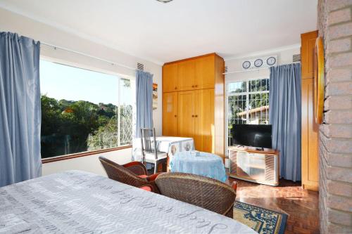 a bedroom with a bed and a tv and a window at Lily's Cottage in Durban