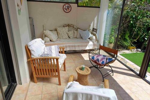 a porch with a couch and chairs on a patio at House 3 rooms with garden near the sea in Bandol