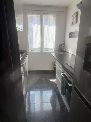 une cuisine avec un évier, une cuisinière et une fenêtre dans l'établissement Appartement au cœur de Rouen, à Rouen