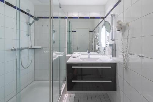 a white bathroom with a sink and a shower at An de See - im Ostseeheilbad Zingst mit Balkon in Zingst