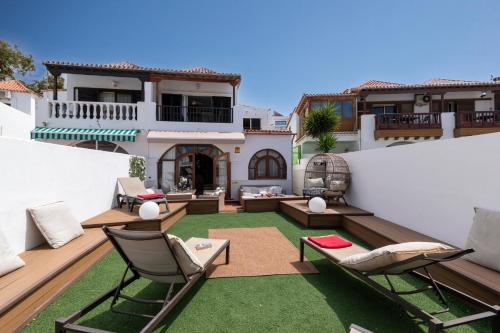 an outdoor patio with chairs and tables on a house at Villa Tricia 6 Bedroom Las Americas in Playa de las Americas