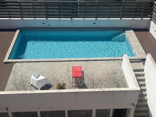 an overhead view of a swimming pool with two red chairs at Casa dos Carvalhos in Coimbra