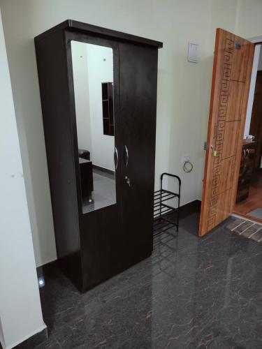 a black cabinet with a mirror and a chair in a room at Samuels Comfort Homes in Bengaluru