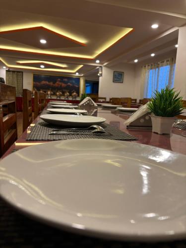 a dining room with a table with white plates on it at Hotel KASTURI PALACE & RESTAURANT DARJEELING in Darjeeling