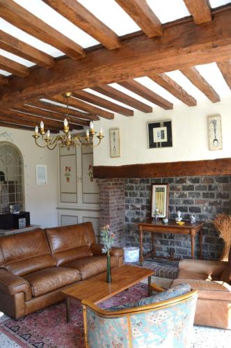 Il comprend un salon doté d'un mobilier en cuir et d'un mur en briques. dans l'établissement L'Orée des Prés - Gîte familial - 4 étoiles - 8 personnes, à Ouville-la-Rivière